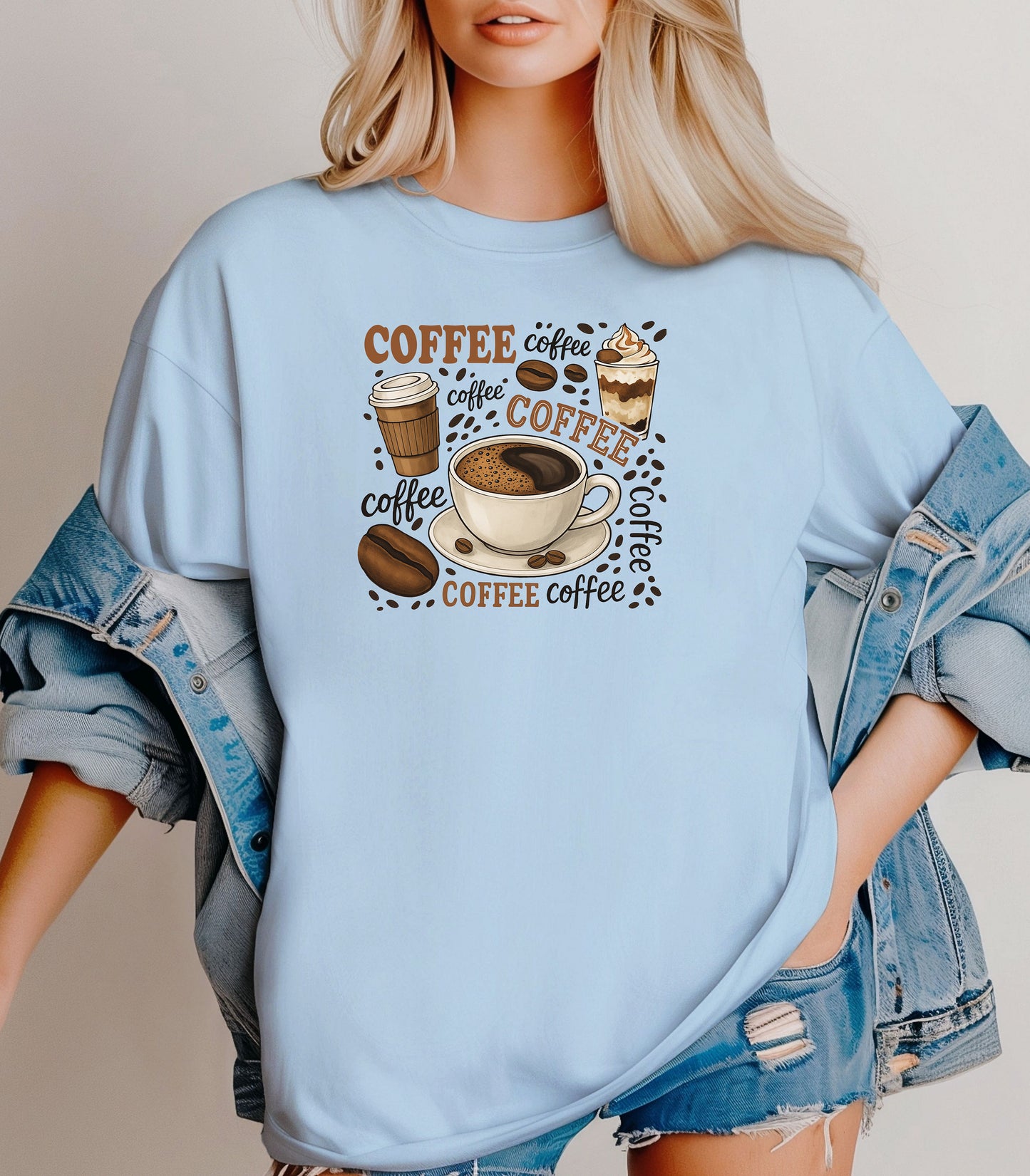 Chambray light blue t-shirt featuring a playful coffee-themed design with multiple illustrated coffee cups, beans, and the word “coffee” repeated in various fonts and styles. Centered around a steaming cup of coffee on a saucer, this fun and cozy graphic is perfect for caffeine lovers who want to show off their coffee obsession in style.