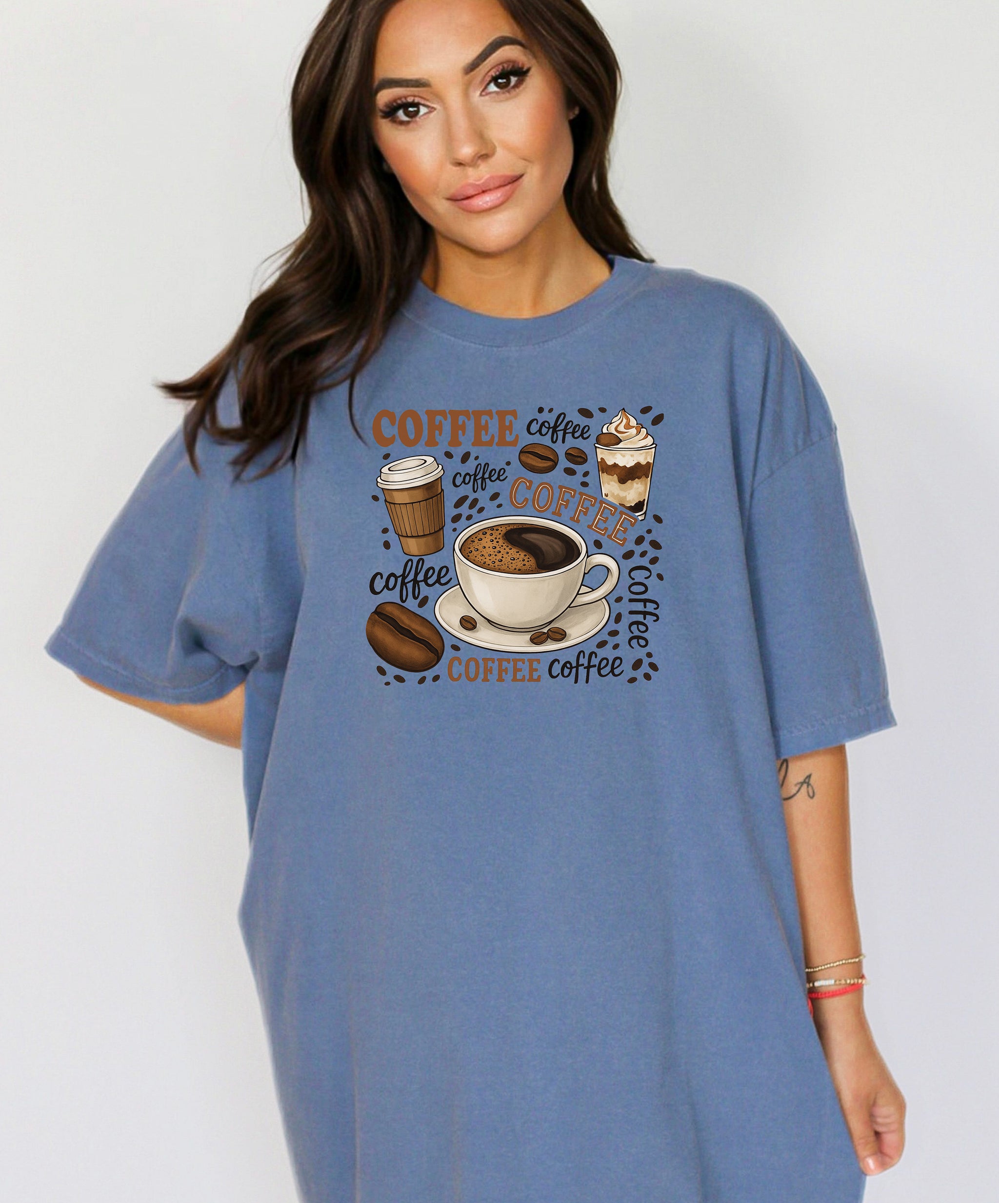 Washed Denim t-shirt featuring a playful coffee-themed design with multiple illustrated coffee cups, beans, and the word “coffee” repeated in various fonts and styles. Centered around a steaming cup of coffee on a saucer, this fun and cozy graphic is perfect for caffeine lovers who want to show off their coffee obsession in style.