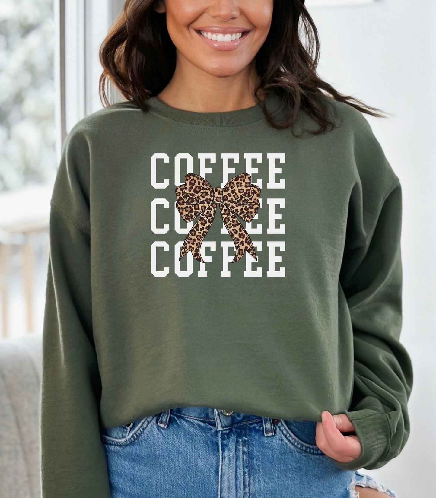 Military Green Gildan sweatshirt featuring a bold white triple “COFFEE” text stacked vertically, accented with a stylish leopard-print coquette bow at the center. A trendy and playful design that blends coffee love with fashionable flair—perfect for cozy mornings and confident, cute style.