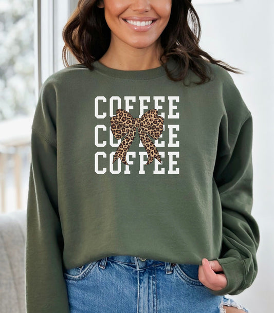 Military Green Gildan sweatshirt featuring a bold white triple “COFFEE” text stacked vertically, accented with a stylish leopard-print coquette bow at the center. A trendy and playful design that blends coffee love with fashionable flair—perfect for cozy mornings and confident, cute style.