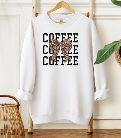 White Gildan sweatshirt featuring a bold black triple “COFFEE” text stacked vertically, accented with a stylish leopard-print coquette bow at the center. A trendy and playful design that blends coffee love with fashionable flair—perfect for cozy mornings and confident, cute style.