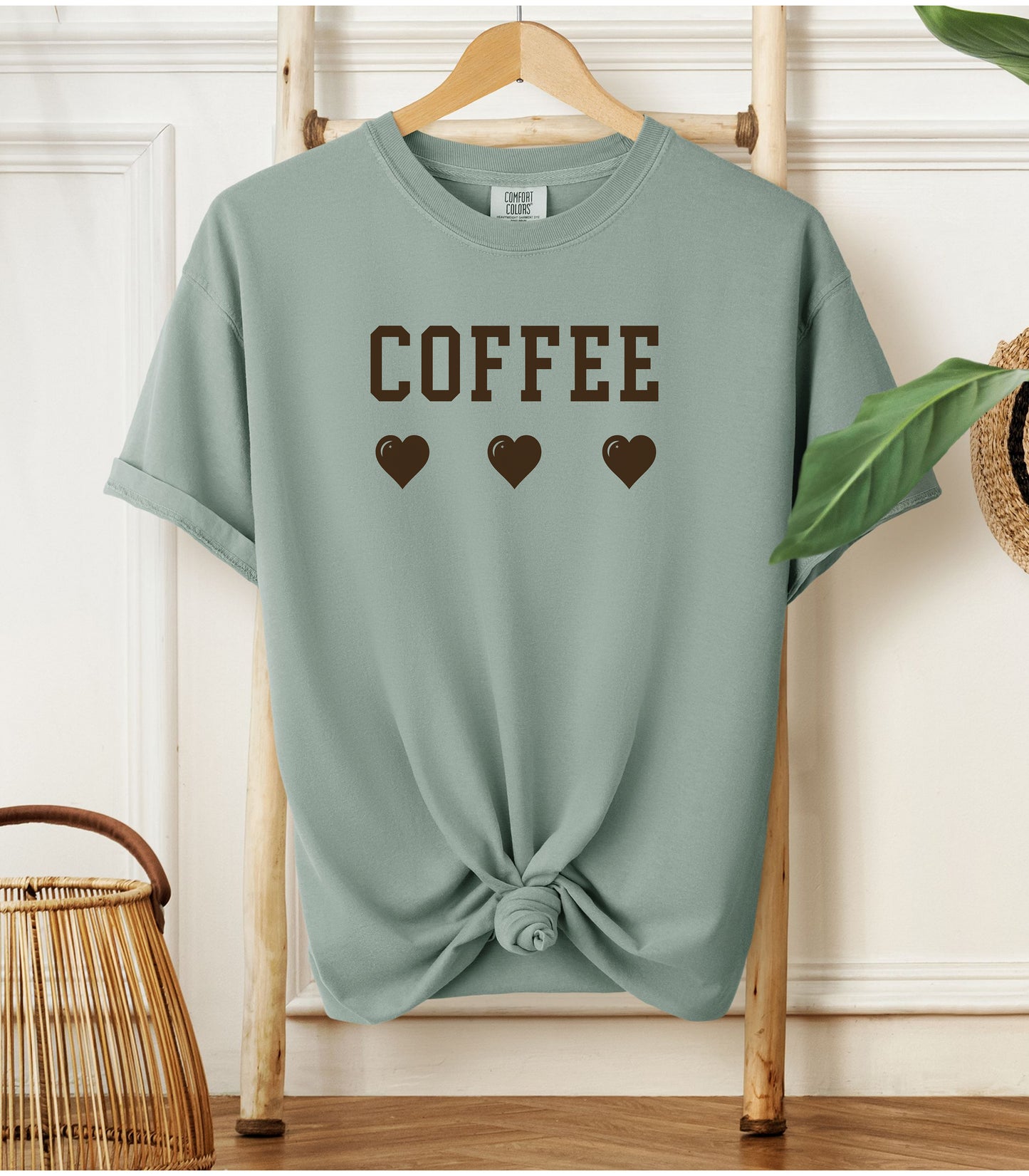 Bay Comfort Colors t-shirt featuring bold brown varsity-style “COFFEE” text above three matching heart icons. Simple and cute design that expresses love for coffee with a soft, cozy aesthetic—perfect for casual wear, coffee dates, or gifting to your favorite caffeine enthusiast.