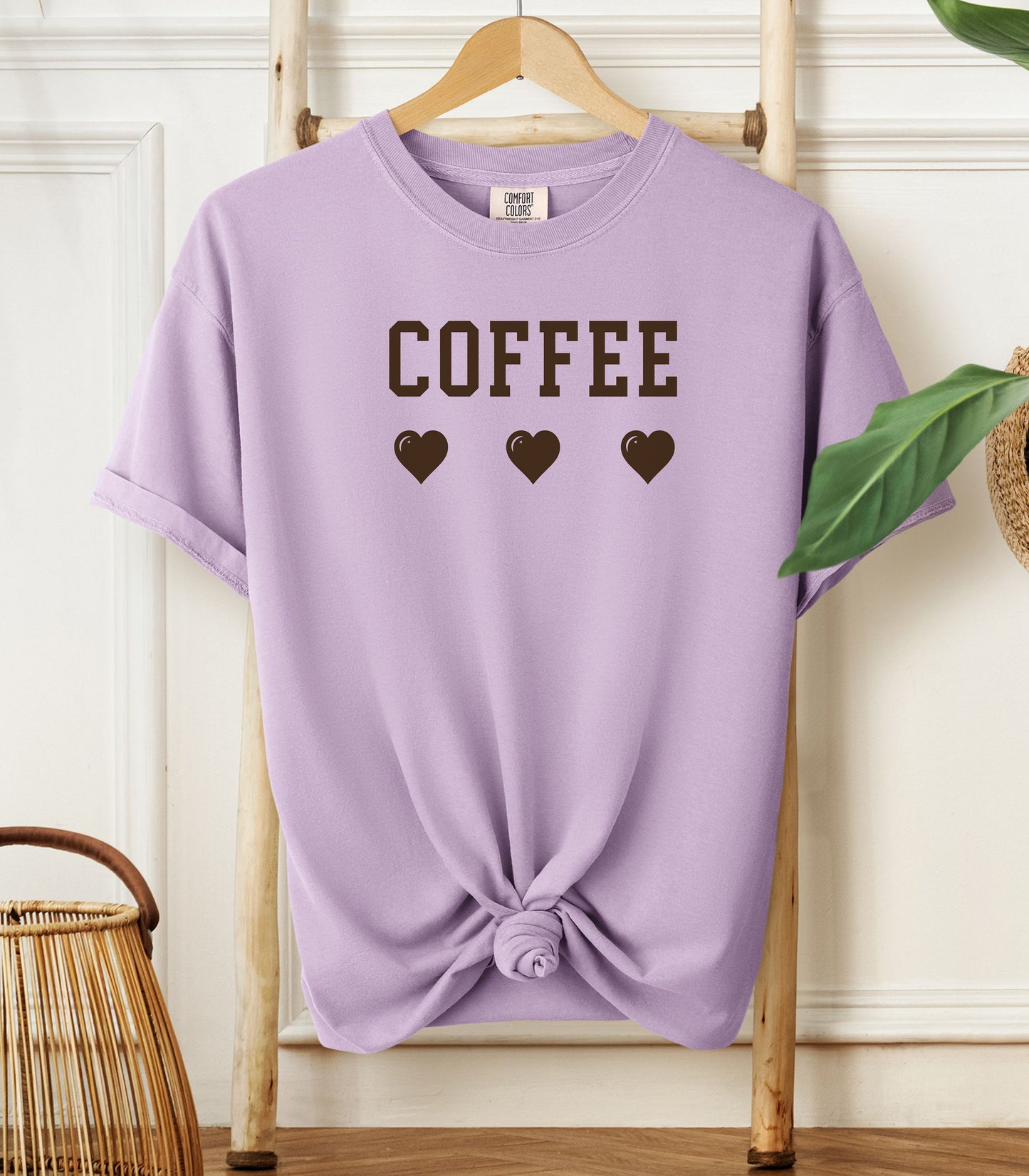 Orchid Comfort Colors t-shirt featuring bold brown varsity-style “COFFEE” text above three matching heart icons. Simple and cute design that expresses love for coffee with a soft, cozy aesthetic—perfect for casual wear, coffee dates, or gifting to your favorite caffeine enthusiast.
