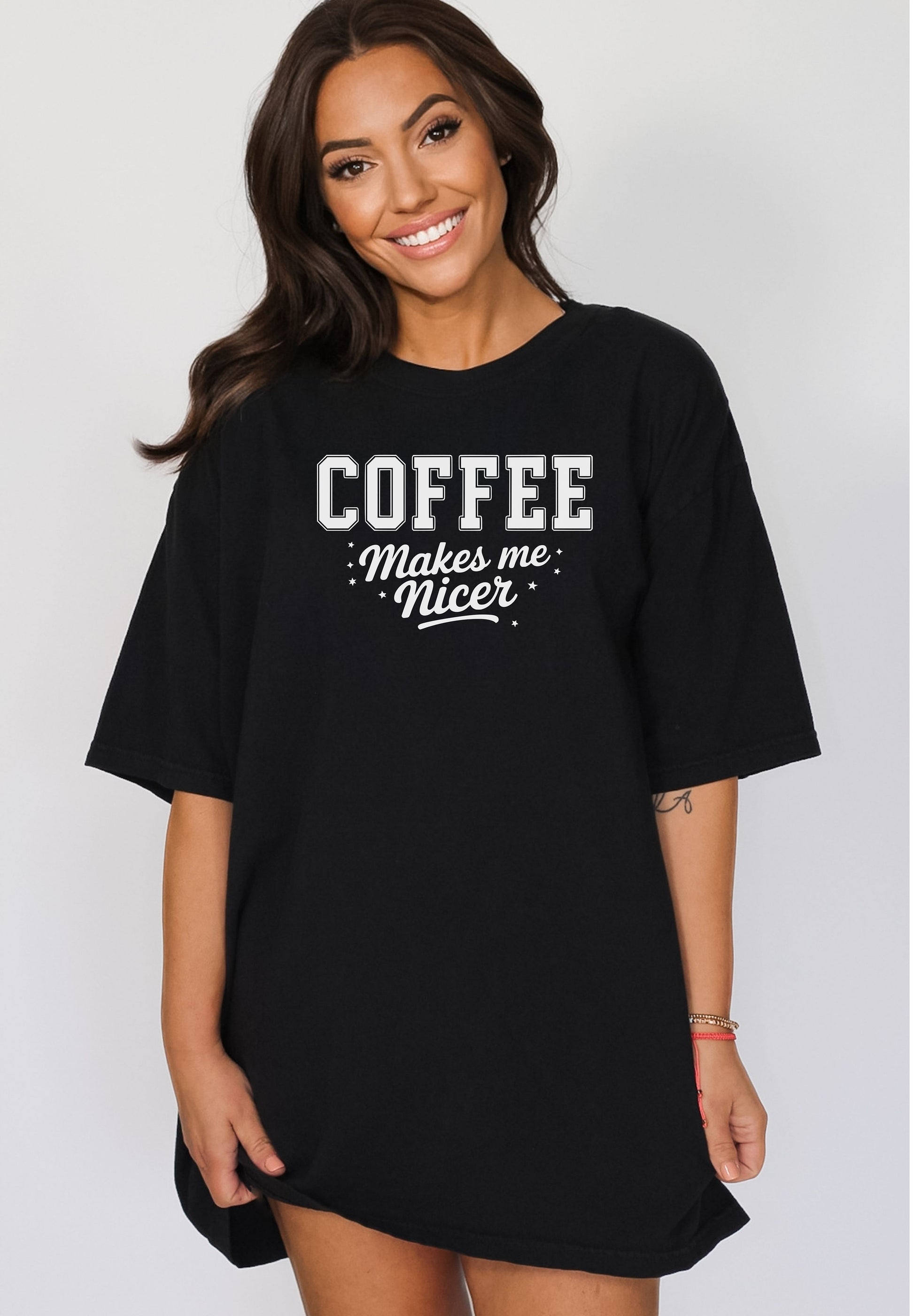 Graphic black t-shirt design featuring bold varsity-style white text “COFFEE” with the phrase “makes me nicer” in a playful script underneath, surrounded by small stars. A fun and relatable design perfect for coffee lovers who know their mood improves with caffeine—ideal for casual wear with a humorous twist.