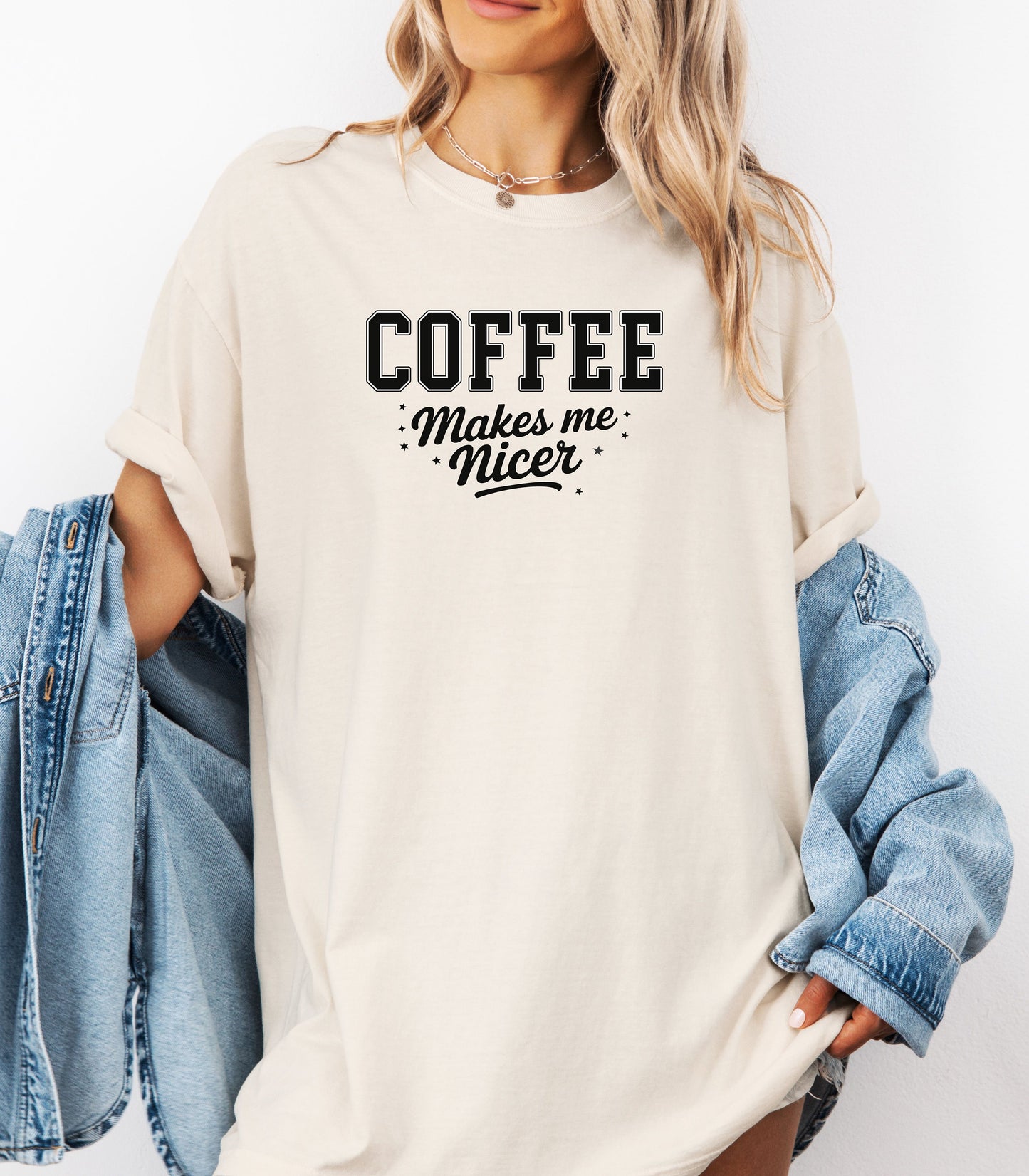 Graphic Ivory t-shirt design featuring bold varsity-style black text “COFFEE” with the phrase “makes me nicer” in a playful script underneath, surrounded by small stars. A fun and relatable design perfect for coffee lovers who know their mood improves with caffeine—ideal for casual wear with a humorous twist.