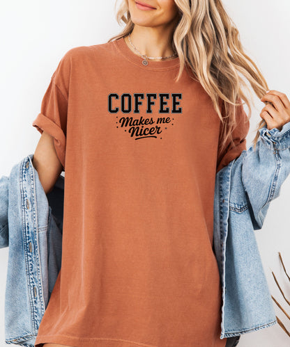 Graphic Yam t-shirt design featuring bold varsity-style black text “COFFEE” with the phrase “makes me nicer” in a playful script underneath, surrounded by small stars. A fun and relatable design perfect for coffee lovers who know their mood improves with caffeine—ideal for casual wear with a humorous twist.