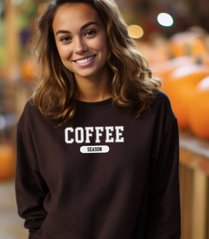 Dark Chocolate sweatshirt featuring a bold “COFFEE” design in varsity-style white lettering with the word “SEASON” underneath in a rounded black label. A cozy and stylish look perfect for coffee lovers embracing their favorite time of year—whether it’s fall, winter, or every season.