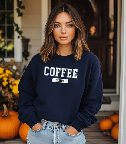 Cream sweatshirt featuring a bold “COFFEE” design in varsity-style white lettering with the word “SEASON” underneath in a rounded black label. A cozy and stylish look perfect for coffee lovers embracing their favorite time of year—whether it’s fall, winter, or every season.