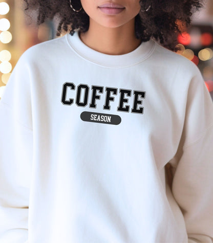 White sweatshirt featuring a bold “COFFEE” design in varsity-style black lettering with the word “SEASON” underneath in a rounded black label. A cozy and stylish look perfect for coffee lovers embracing their favorite time of year—whether it’s fall, winter, or every season.