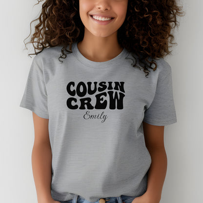 Smiling child wearing an Athletic Heather youth T-shirt with bold black "Cousin Crew" text in a playful font and personalized with “Your Name” in elegant script below. The shirt is paired with jeans, creating a fun and youthful vibe perfect for family gatherings or matching cousin outfits.