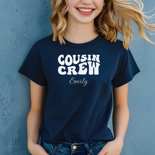 Smiling child wearing a navy blue youth T-shirt with bold white "Cousin Crew" text in a playful font and personalized with “Your Name” in elegant script below. The shirt is paired with jeans, creating a fun and youthful vibe perfect for family gatherings or matching cousin outfits.