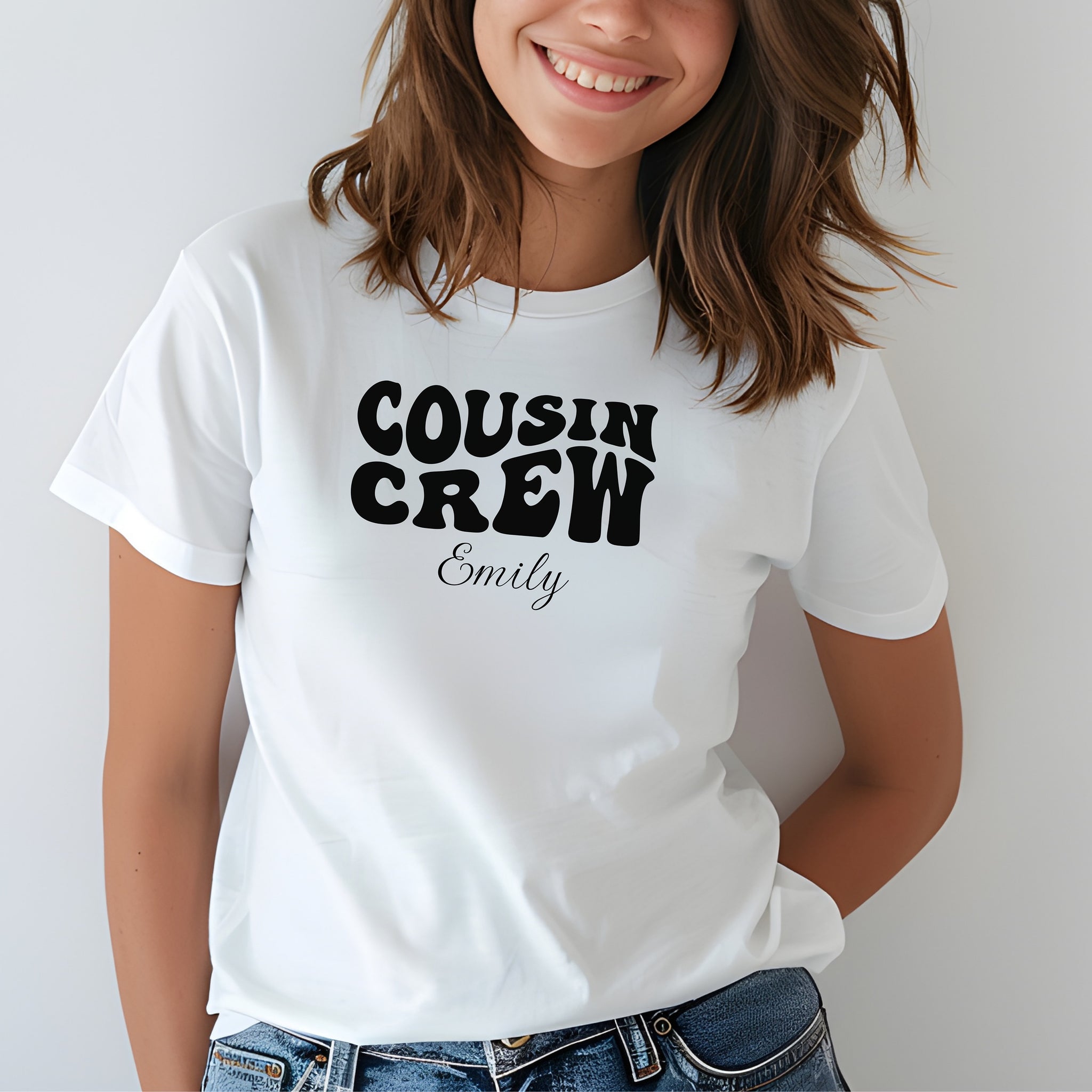 Smiling child wearing a White youth T-shirt with bold black "Cousin Crew" text in a playful font and personalized with “Your Name” in elegant script below. The shirt is paired with jeans, creating a fun and youthful vibe perfect for family gatherings or matching cousin outfits.