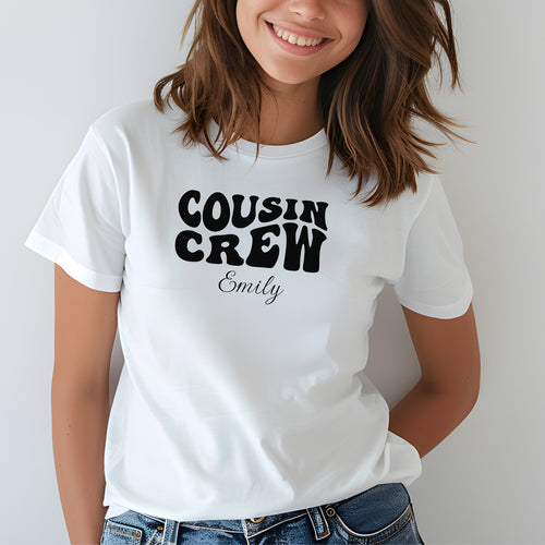 Smiling child wearing a White youth T-shirt with bold black "Cousin Crew" text in a playful font and personalized with “Your Name” in elegant script below. The shirt is paired with jeans, creating a fun and youthful vibe perfect for family gatherings or matching cousin outfits.