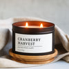 Cranberry Harvest candle in a black matte 8 oz candle tin with a wooden coaster on a neutral background