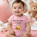 Infant wearing a pink infant bodysuit featuring the phrase "Cutest Little Pumpkin In The Patch" with an adorable fall-themed design of orange and white pumpkins, autumn leaves, hearts, and a sweet bow. Perfect for baby's first fall or pumpkin patch visit.