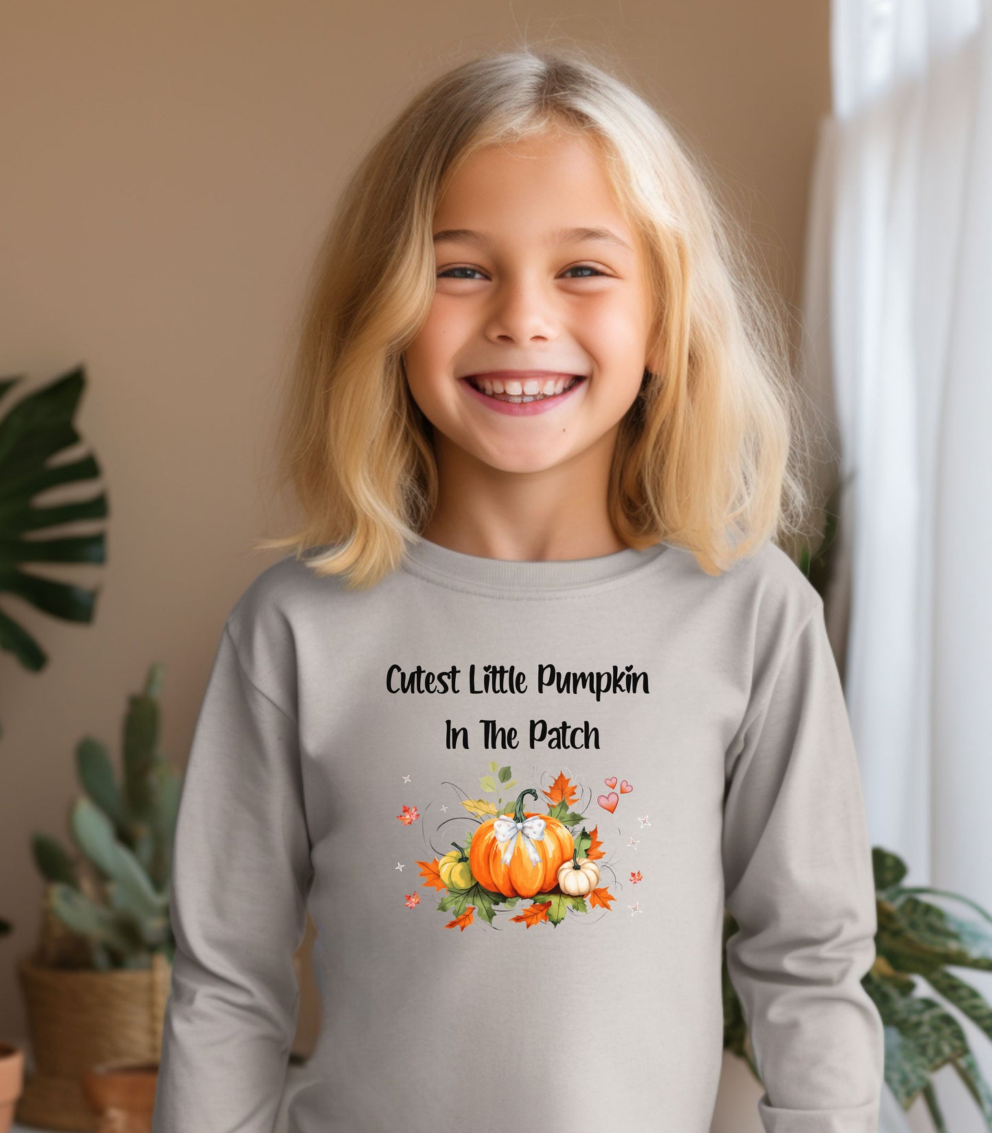 Older Toddler wearing a Heather long sleeve shirt with 'Cutest Little Pumpkin In The Patch' text and pumpkin graphics.