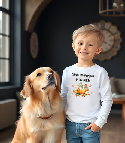Toddler wearing a white long sleeve shirt with 'Cutest Little Pumpkin In The Patch' text and pumpkin graphics.
