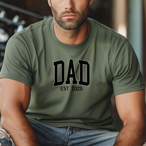 Personalized DAD Est [Year] T-shirt featuring bold varsity-style block lettering with a customizable establishment year. Printed on a soft, relaxed-fit unisex tee in moss, this design is perfect for celebrating new or seasoned fathers. Ideal for Father’s Day, birthdays, or family milestones, offering both comfort and a proud personal touch.