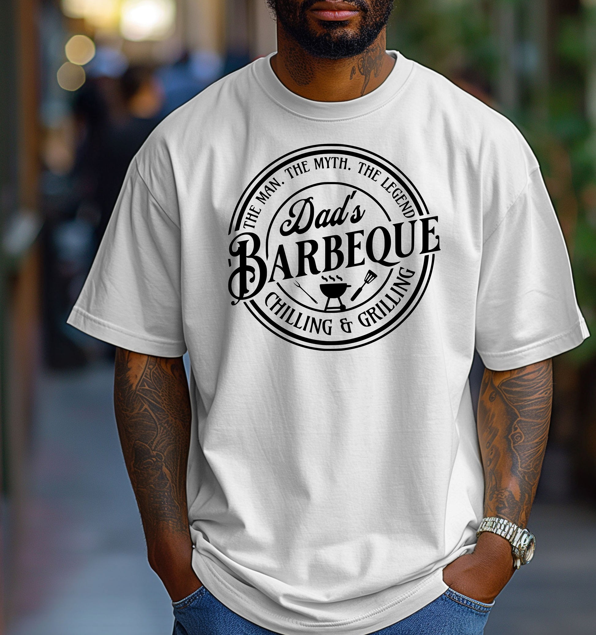 Dad’s Barbeque T-shirt featuring a circular badge-style design with the phrases 'The Man. The Myth. The Legend.' and 'Chilling & Grilling.' The center showcases 'Dad’s Barbeque' in bold lettering with a small grill, fork, and spatula icons. Printed on a classic white unisex tee, this shirt is perfect for BBQ-loving dads and makes a fun Father’s Day or birthday gift.