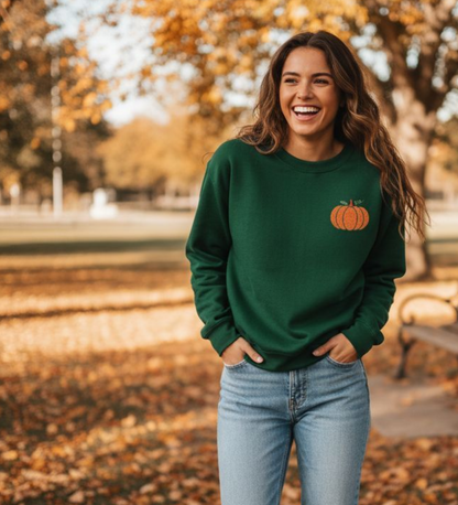 Person wearing a Forest Green sweatshirt with an embroidered pumpkin design, outdoors