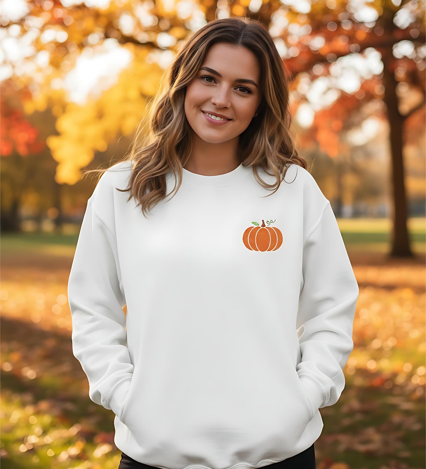 Person wearing a white sweatshirt with an embroidered pumpkin design, outdoors