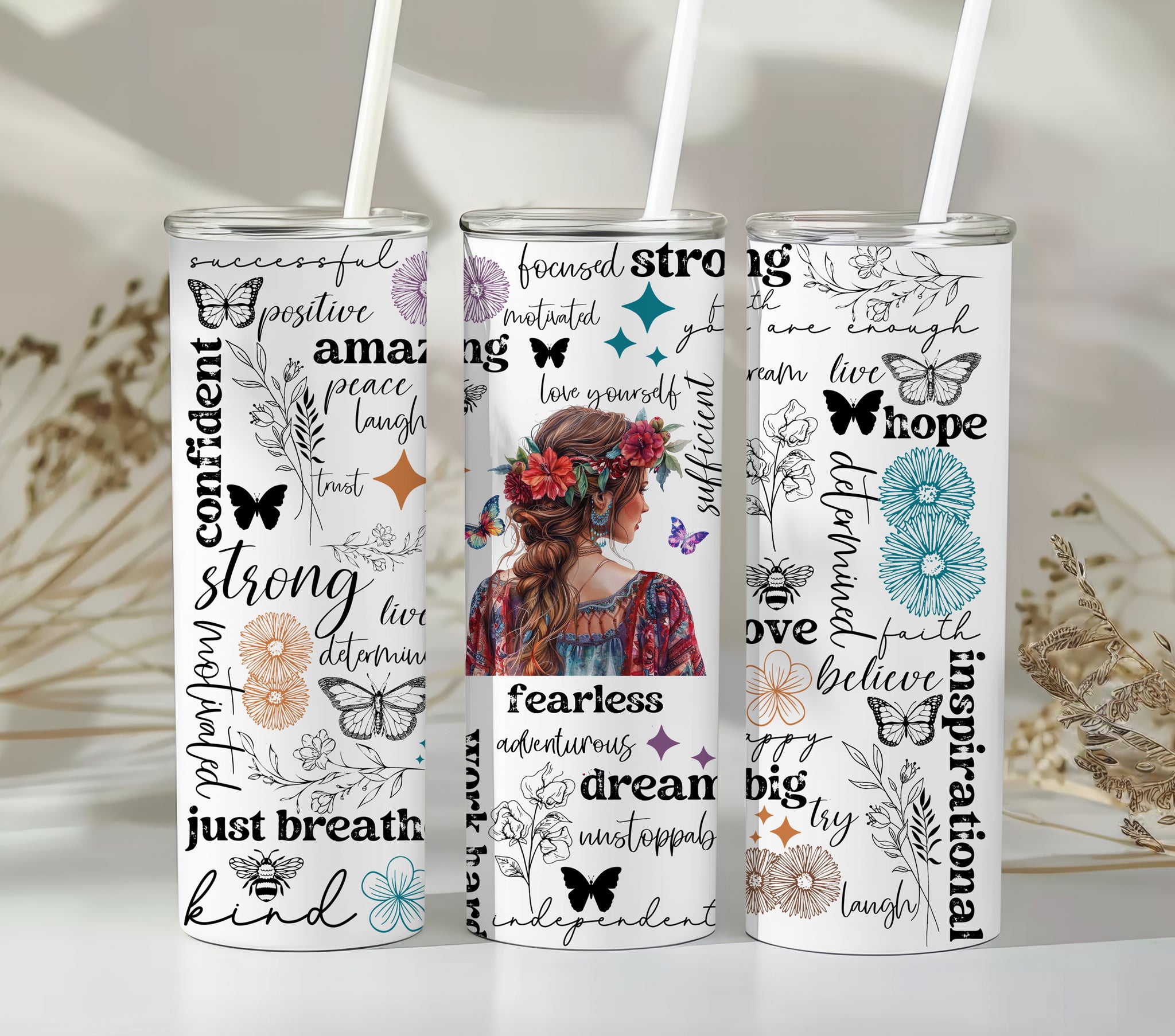 Empowering Motivational Skinny Tumbler – 20 oz featuring an artistic design with a woman adorned in a floral crown on the back and surrounded by uplifting words like strong, fearless, confident, love, believe, and inspirational. Accented with butterflies, bees, and flowers, this reusable stainless steel tumbler is perfect for keeping drinks hot or cold while inspiring positivity and self-confidence every day.