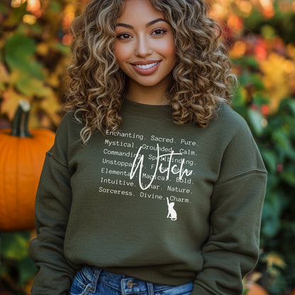 Person wearing a Miliary Green sweatshirt with text and a witch symbol, standing in front of pumpkins and foliage.