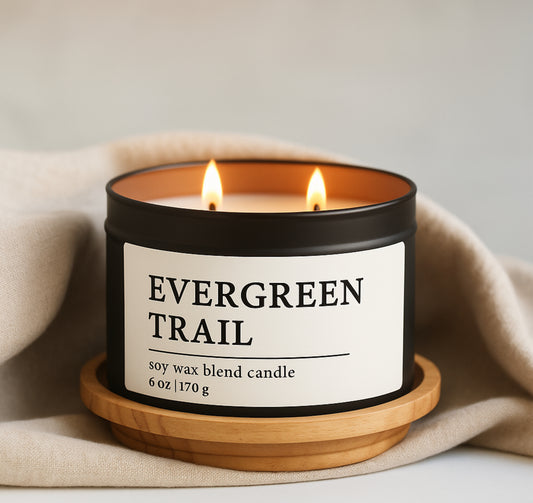 Soy wax blend candle labeled 'Evergreen Trail' on a wooden coaster with a beige fabric background