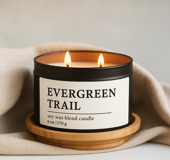 Evergreen Trail Soy Wax Blend Candle in a 8 oz black matte candle tin on a wooden coaster with a beige fabric background