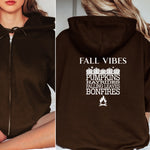 Dark Chocolate Gildan hoodie featuring a white“FALL VIBES” design on the back with stacked seasonal words: “PUMPKINS, HAYRIDES, FALLING LEAVES, BONFIRES,” framed by pumpkins above and a bonfire icon below. A cozy, festive graphic perfect for autumn lovers and fall adventures.