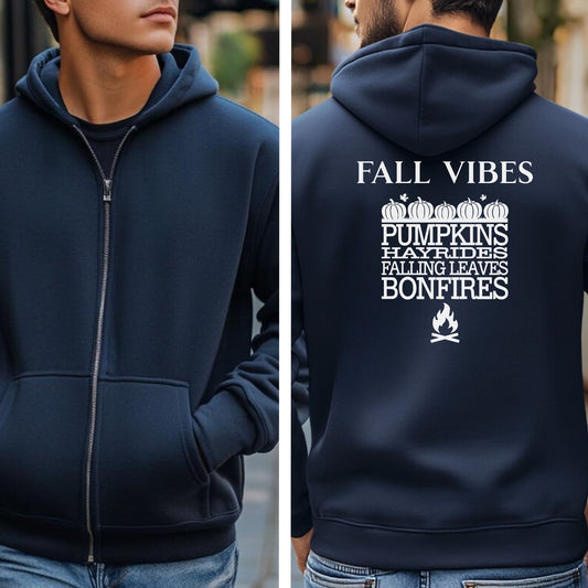 Navy Gildan hoodie featuring a white “FALL VIBES” design on the back with stacked seasonal words: “PUMPKINS, HAYRIDES, FALLING LEAVES, BONFIRES,” framed by pumpkins above and a bonfire icon below. A cozy, festive graphic perfect for autumn lovers and fall adventures.