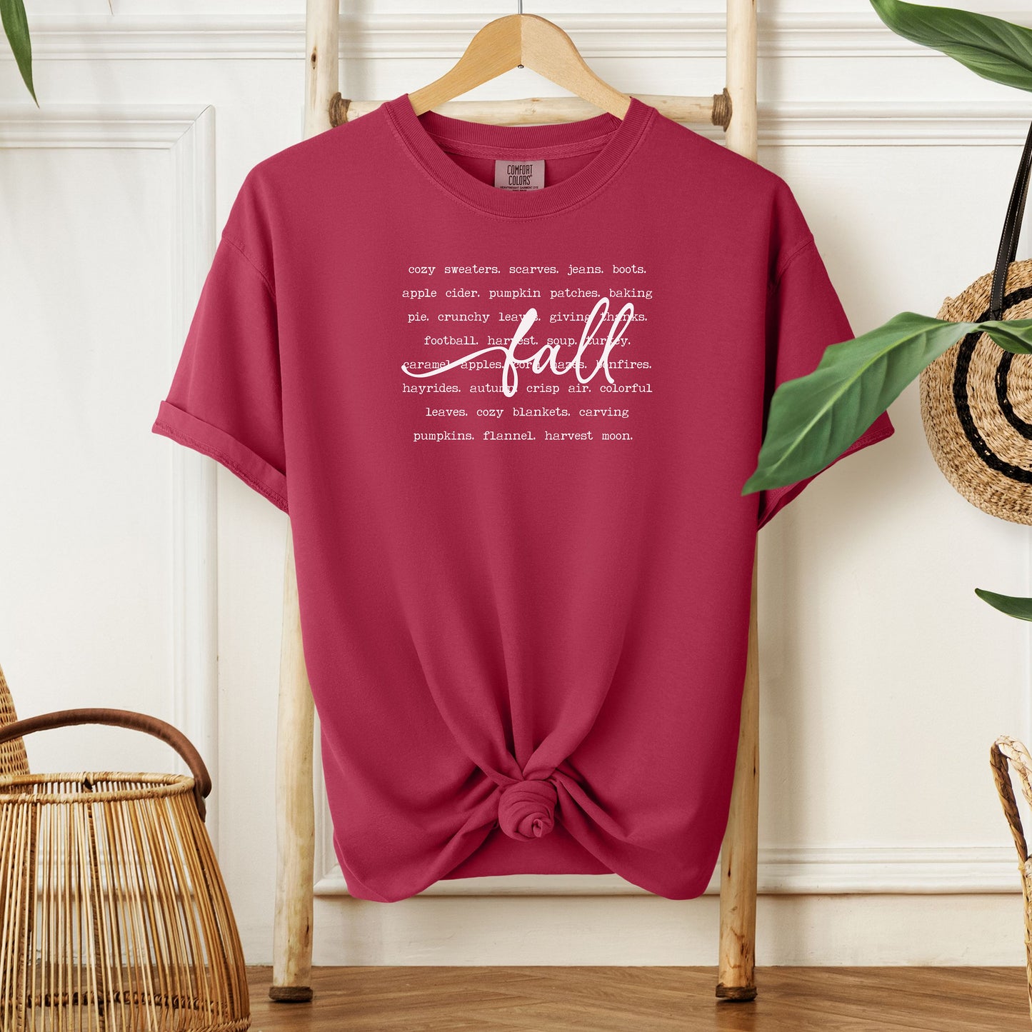 Chili T-shirt with a cozy fall-themed text design featuring words like cozy sweaters, pumpkin patches, apple cider, hayrides, football, bonfires, flannel, and harvest moon. The word “Fall” stands out in a large handwritten script across the center, celebrating autumn vibes and seasonal favorites. Perfect for fall lovers and casual outfits.