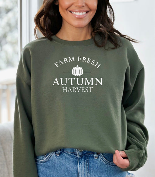 Military Green Gildan sweatshirt featuring a minimalist white “Farm Fresh Autumn Harvest” design with a simple pumpkin graphic in the center. A clean and classic fall look that captures rustic charm and seasonal spirit—perfect for farmers' markets, pumpkin patches, and cozy autumn days.