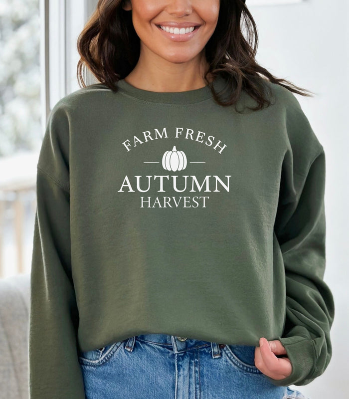 Military Green Gildan sweatshirt featuring a minimalist white “Farm Fresh Autumn Harvest” design with a simple pumpkin graphic in the center. A clean and classic fall look that captures rustic charm and seasonal spirit—perfect for farmers' markets, pumpkin patches, and cozy autumn days.