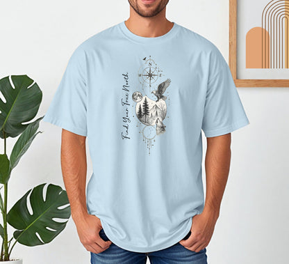 Person wearing a chambray light blue T-shirt featuring a “Find Your True North” design with a vertical compass, full moon, pine trees, mountains, soaring eagle, and howling wolf in detailed black and white sketch style. The design blends celestial and wilderness elements, symbolizing adventure, guidance, and a connection to nature. Perfect for outdoor lovers, travelers, and free spirits seeking inspiration and direction.