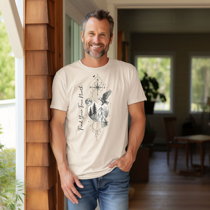 Person wearing an ivory T-shirt featuring a “Find Your True North” design with a vertical compass, full moon, pine trees, mountains, soaring eagle, and howling wolf in detailed black and white sketch style. The design blends celestial and wilderness elements, symbolizing adventure, guidance, and a connection to nature. Perfect for outdoor lovers, travelers, and free spirits seeking inspiration and direction.