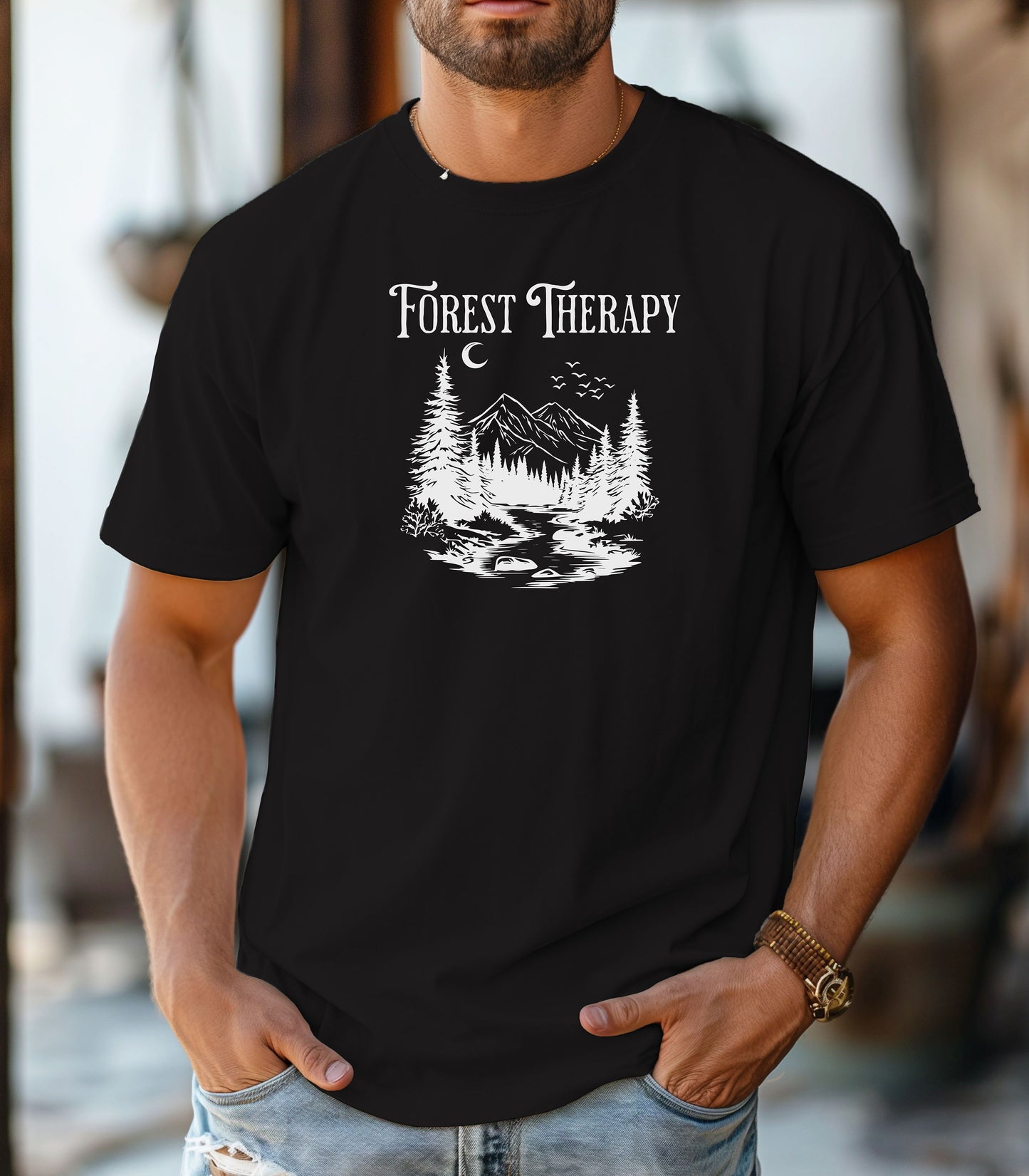 Person wearing a black t-shirt featuring a white “Forest Therapy” design with a peaceful mountain scene, pine trees, a flowing river, birds, and a crescent moon. The perfect tee for nature lovers, hikers, and outdoor enthusiasts seeking serenity and scenic vibes.