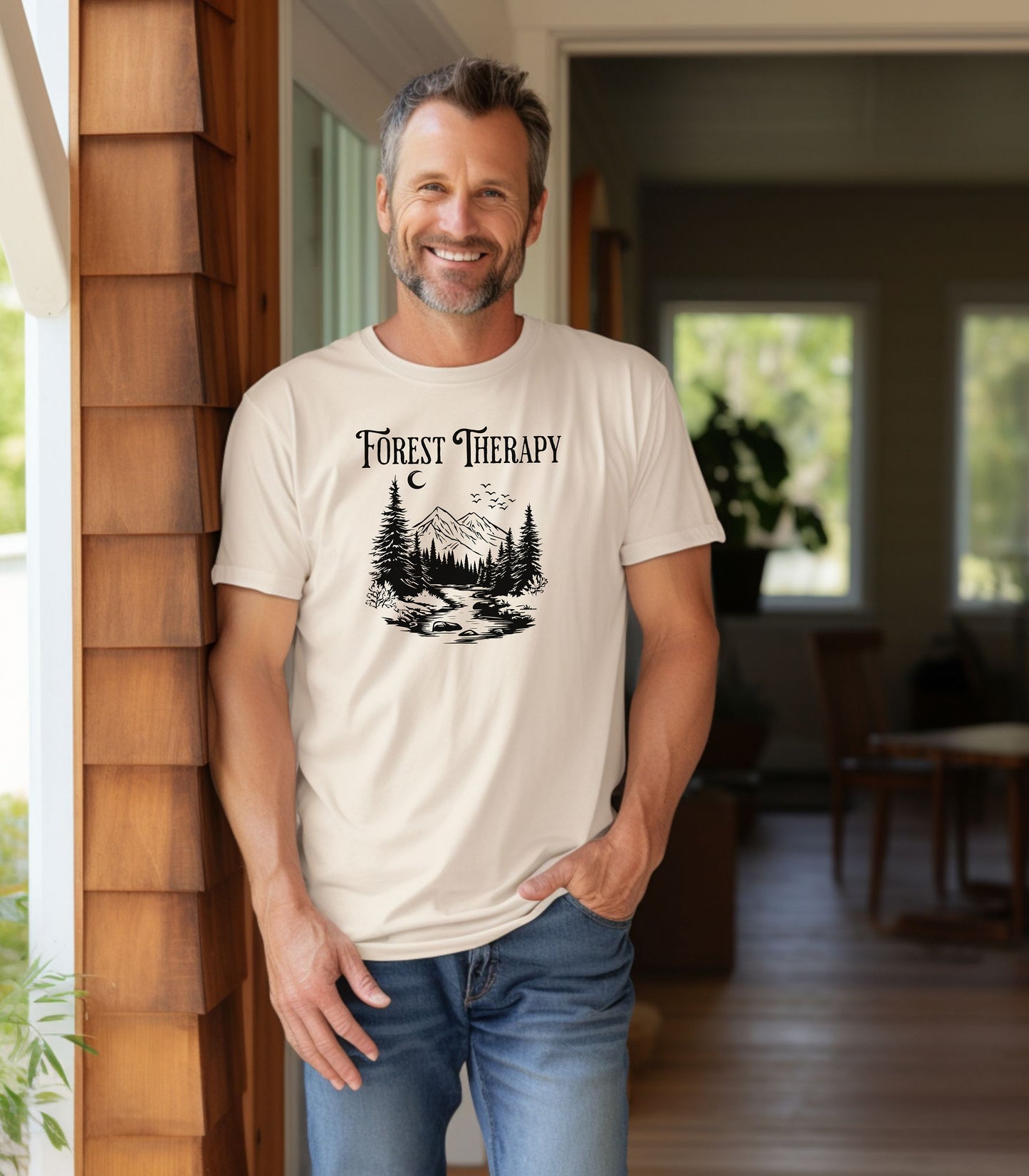 Person wearing an Ivory t-shirt featuring a black “Forest Therapy” design with a peaceful mountain scene, pine trees, a flowing river, birds, and a crescent moon. The perfect tee for nature lovers, hikers, and outdoor enthusiasts seeking serenity and scenic vibes.