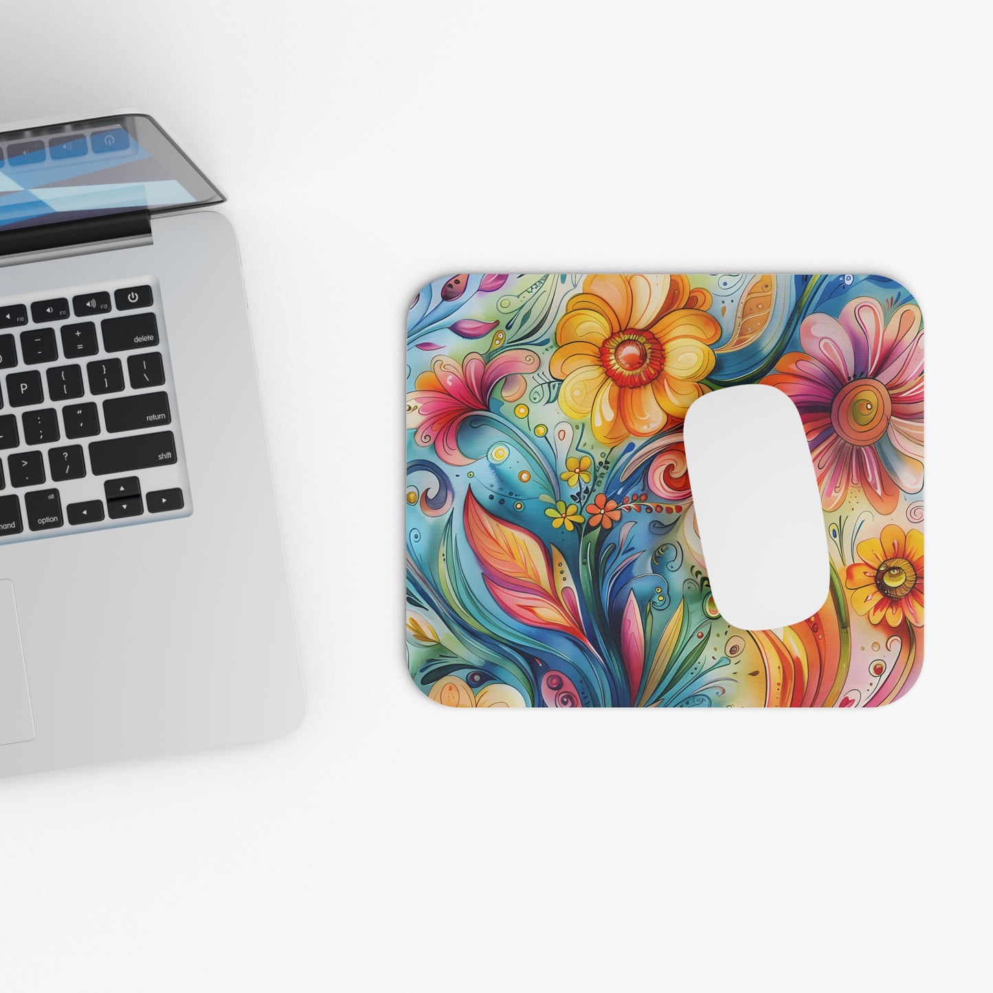Colorful floral mouse pad next to a laptop on a white surface
