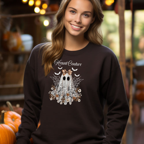 Dark Chocolate Gildan sweatshirt featuring a stylish “Haunt Couture” design with a chic ghost draped in lace, wearing a metallic bow, surrounded by floral accents, spiderwebs, and flying bats. A glamorous and spooky Halloween look that blends fashion and festive charm—perfect for fall outings and haunted style.