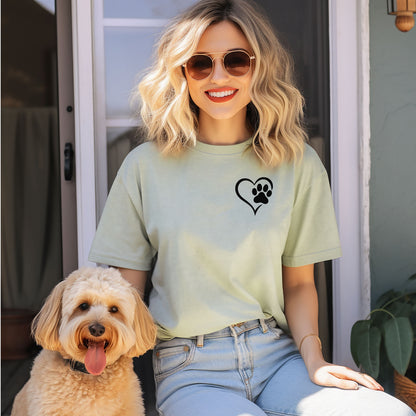 Person wearing a classic bay T-shirt featuring a simple black heart outline with a paw print inside on the upper left chest. The minimalist Heart Paw Print design symbolizes love for pets, making it a perfect shirt for dog and cat lovers.