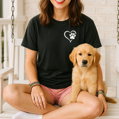 Person wearing a black T-shirt featuring a simple white heart outline with a paw print inside on the upper left chest. The minimalist Heart Paw Print design symbolizes love for pets, making it a perfect shirt for dog and cat lovers.