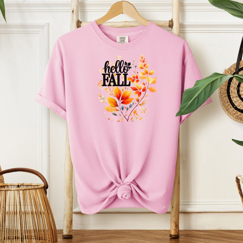 Blossom pink T-shirt featuring a vibrant "Hello Fall" design with hand-painted autumn leaves in orange, yellow, and soft grey blue tones. The bold black lettering is accented by delicate foliage, giving this seasonal tee a cozy, cheerful, and nature-inspired look perfect for fall fashion.