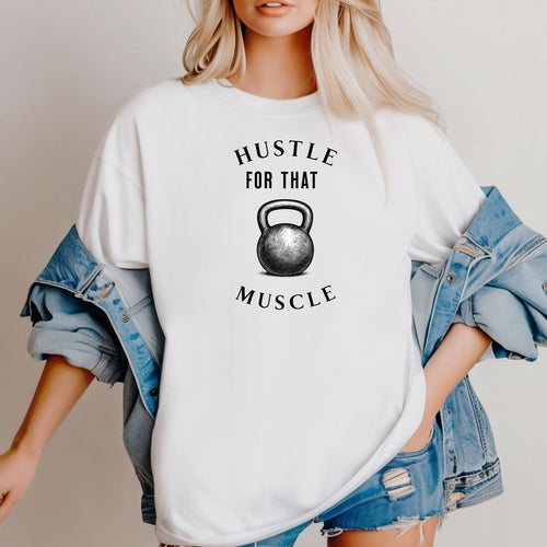 Person wearing a classic white T-shirt with the phrase “Hustle For That Muscle” in bold black text, arched above and below a detailed kettlebell graphic. The design blends minimalist style with fitness motivation, perfect for gym-goers, weightlifters, and strength training enthusiasts who embrace hard work and dedication in their workout journey.