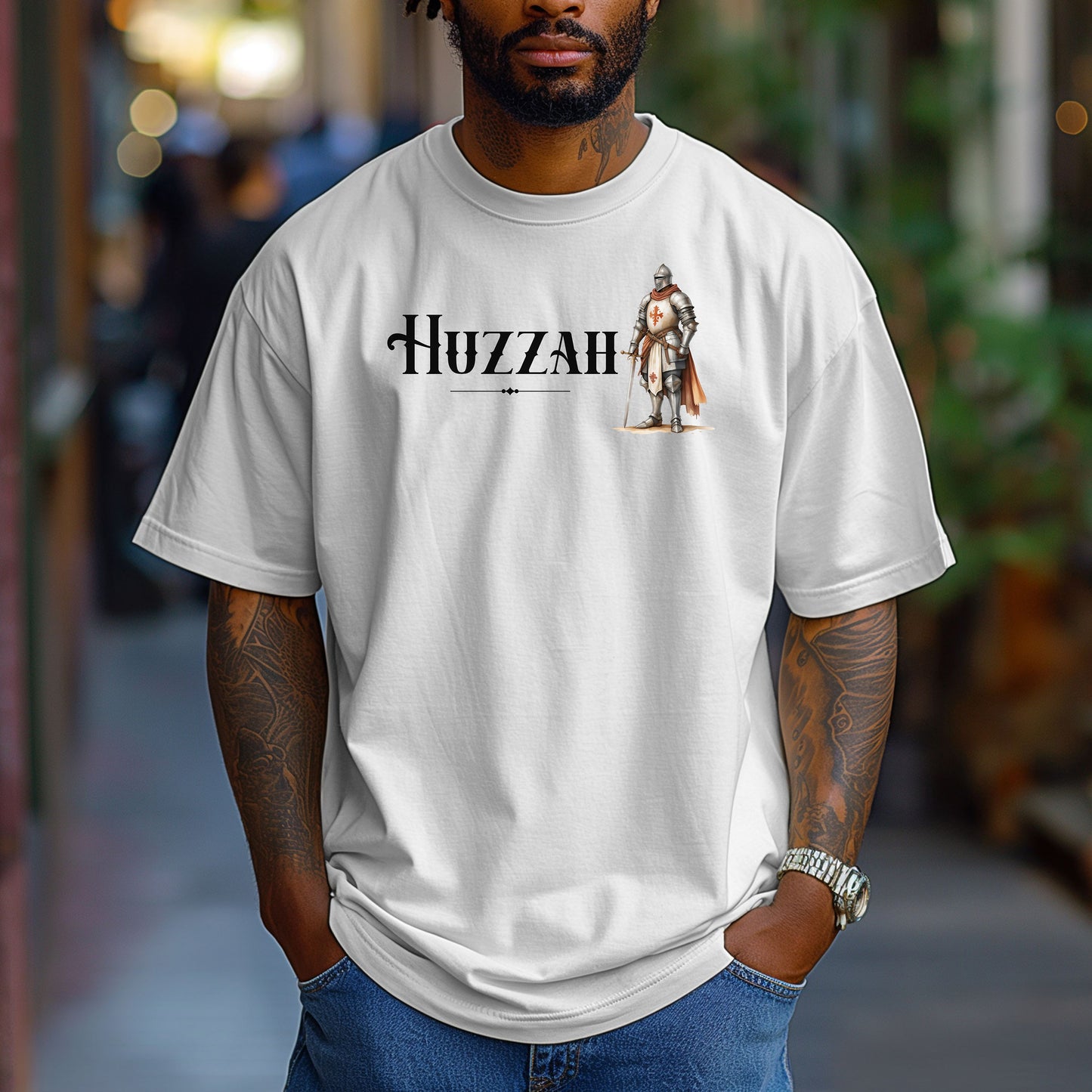 White T-shirt featuring a Renaissance Faire design with the word “Huzzah” in medieval-style lettering and an illustration of a knight in shining armor. Perfect for Renaissance fair goers, medieval enthusiasts, and fans of historical festivals, celebrating the lively and spirited call of “Huzzah” at fairs and events.
