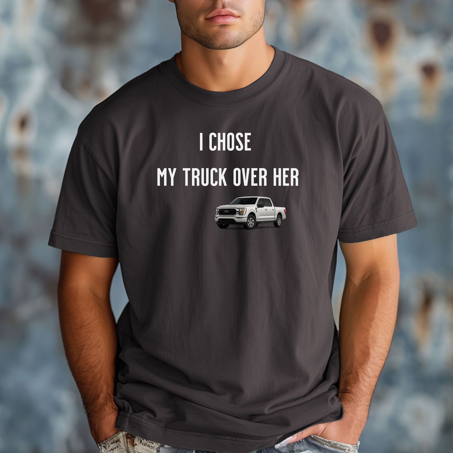 Graphite T-shirt featuring the bold black text "I Chose My Truck Over Her" with a graphic of a white pickup truck beneath the words. The design has a humorous, confident tone, appealing to truck lovers and automotive enthusiasts. 