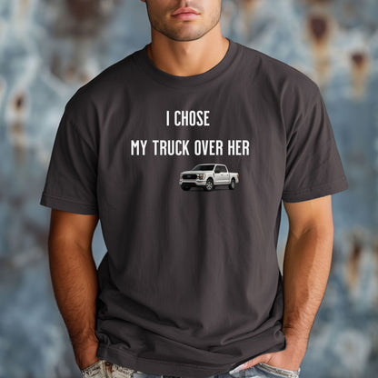 Graphite T-shirt featuring the bold black text "I Chose My Truck Over Her" with a graphic of a white pickup truck beneath the words. The design has a humorous, confident tone, appealing to truck lovers and automotive enthusiasts. 