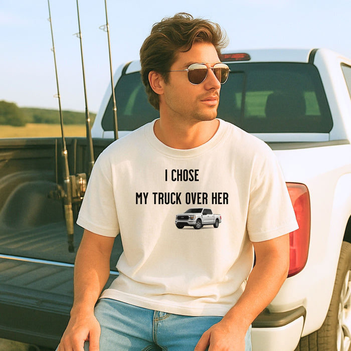 Ivory T-shirt featuring the bold black text "I Chose My Truck Over Her" with a graphic of a white pickup truck beneath the words. The design has a humorous, confident tone, appealing to truck lovers and automotive enthusiasts. 