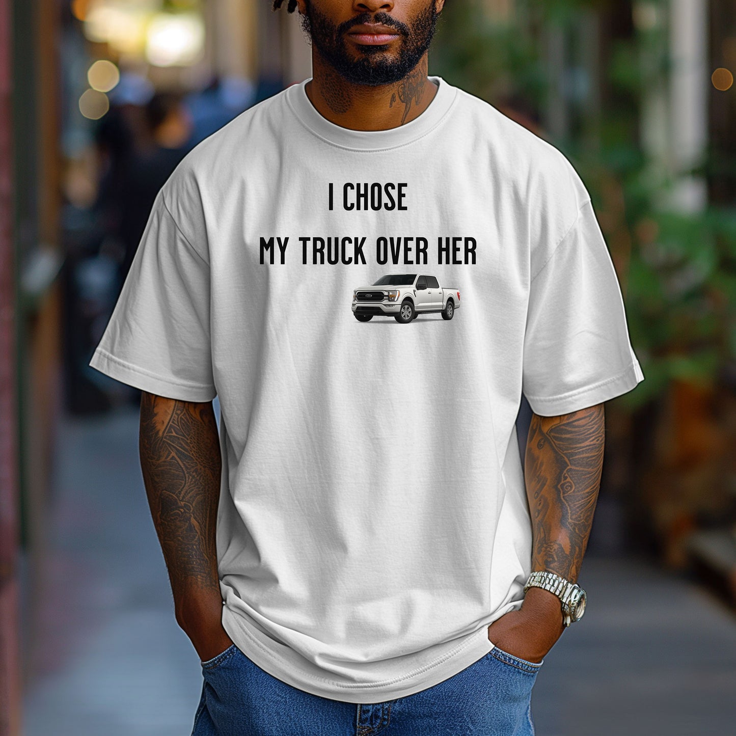 White T-shirt featuring the bold black text "I Chose My Truck Over Her" with a graphic of a white pickup truck beneath the words. The design has a humorous, confident tone, appealing to truck lovers and automotive enthusiasts. 