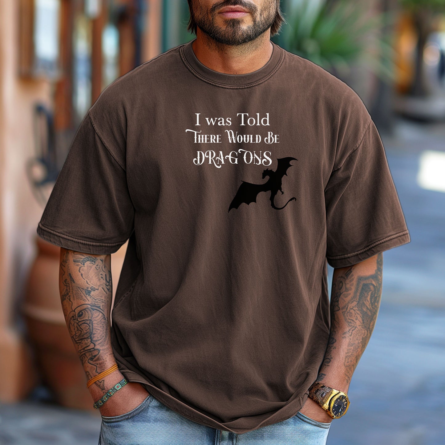 Person wearing an Espresso T-shirt with a Renaissance Faire-inspired design that reads “I Was Told There Would Be Dragons” in medieval-style fonts. The graphic features a bold silhouette of a flying dragon, perfect for fantasy lovers and fairgoers who enjoy whimsical and mythical-themed apparel.
